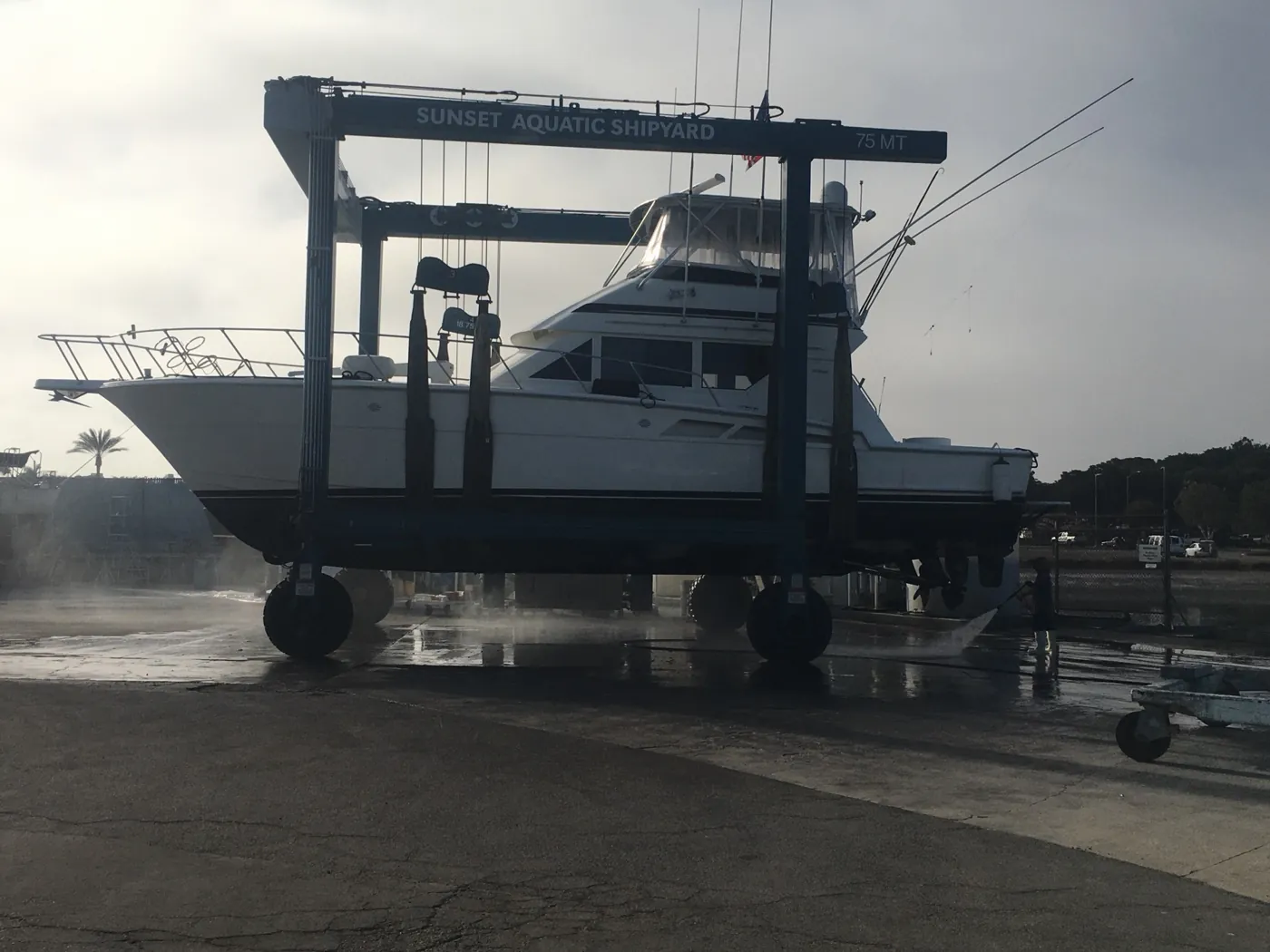 Sportfisher on the travel lift at Sunset Aquatic Shipyard, hull still wet from the wash